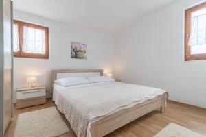 een witte slaapkamer met een bed en 2 ramen bij Apartment Summer in Sukošan