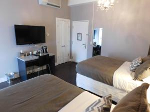 a hotel room with two beds and a desk and a television at The Gould Hotel in Seneca Falls