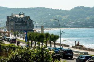 una spiaggia con un edificio e auto parcheggiate accanto all'acqua di Première ligne de plage, face à la mer a Hendaye