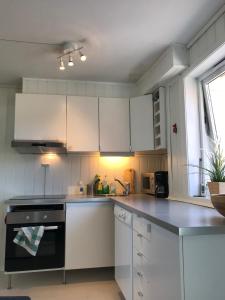 a kitchen with white cabinets and a black stove top oven at Bergen City Apartments Halvkannesmauet in Bergen