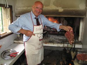 a man in a kitchen holding a piece of meat at Agriturismo Manetti in Montespertoli