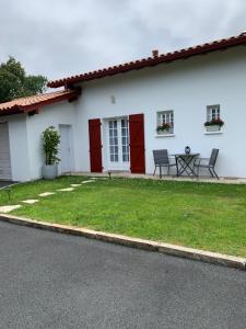 a white house with red doors and a yard at Villa Les Hortensias B&B in Arcangues