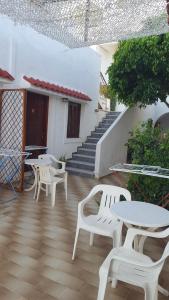 a patio with white tables and chairs and stairs at Aeolos Hotel Apartments in Gythio