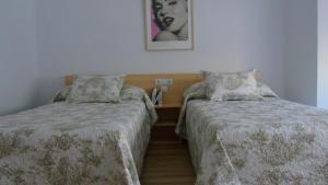 Un dormitorio con 2 camas y una mesa con una foto. en PENSION OVIEDO en Oviedo