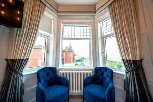 two blue chairs in a room with two windows at The Strand Hotel former Home of Oscar Wilde & Caffe Vergnano 1882 in Bray