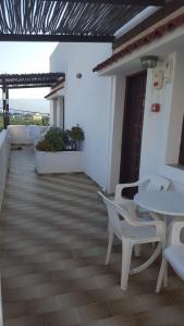 a patio with white chairs and tables on a building at Aeolos Hotel Apartments in Gythio