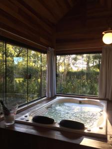 bañera grande en una habitación con ventanas en Pousada Villa do Luar, en Monte Verde