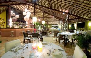 um restaurante com mesas e cadeiras brancas e um bar em GIRASSÓIS - Suítes em Pipa