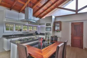 a large kitchen with a wooden table and a kitchen island at Pousada Villa Belle Chalés in Campos do Jordão