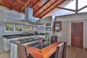 cocina grande con mesa de madera y isla de cocina en Pousada Villa Belle Chalés en Campos do Jordão