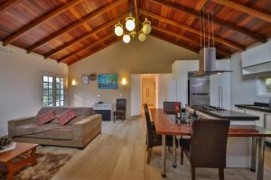 eine Küche und ein Wohnzimmer mit einem Sofa und einem Tisch in der Unterkunft Pousada Villa Belle Chalés in Campos do Jordão
