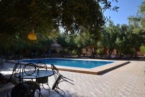 Una mesa y sillas junto a una piscina. en bassou luxury camp, en Merzouga