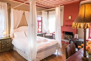 ein Schlafzimmer mit einem Himmelbett und einem Kamin in der Unterkunft Primoula Country Hotel & Spa in Ano Pedina
