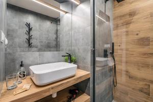 ein Badezimmer mit einem weißen Waschbecken und einer Dusche in der Unterkunft Gold Apartments Your Holiday Home RODZINNY 27 in Krynica-Zdrój