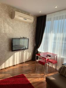 een woonkamer met een tafel en een tv aan de muur bij Most City Riverview in Dnipro