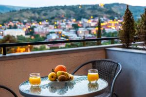 a table with a bowl of fruit and two glasses of orange juice at Tonusi Luxe Hotel in the Historic City Center in Tbilisi City