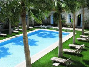 una piscina con palmeras y tumbonas en Manastir Alacati Hotel, en Alacati