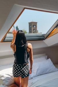 a woman standing on a bed in front of a window at Exclusive Aparthotel La Reunion in Ravenna