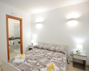 a white bedroom with a bed and a mirror at La casa di Cristina in Avola