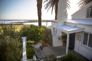 a white house with a porch with a view of the ocean at Palm Villa Cottage in Kommetjie