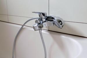 a shower with a hose attached to a white wall at Ferienzimmer Ellisee, kontaktloser Check-in in Friedrichshafen +22 photos