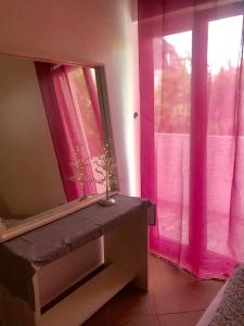 een kamer met een spiegel en een raam met roze gordijnen bij Apartments Ivanišević in Kotor