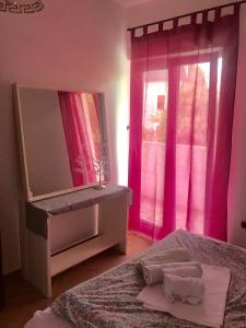 een slaapkamer met roze gordijnen, een spiegel en 2 bedden bij Apartments Ivanišević in Kotor