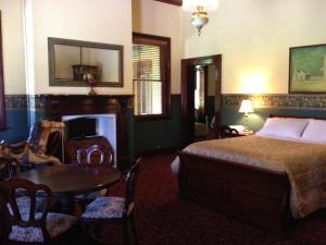 a room with a bed, chair, table and a lamp at Ranelagh House in Dubbo