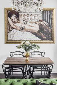 a dining room table with a vase of flowers and a painting at Four Luxury flats in Kaunas