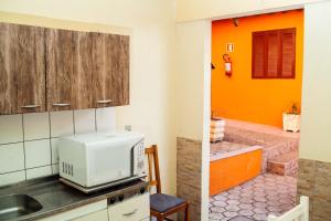 a kitchen with an orange wall and a microwave at Pousada Barth in Canela