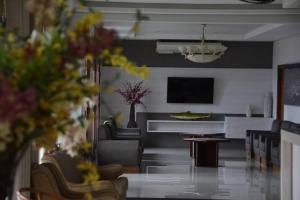 a living room with couches and a television and flowers at Santa Mônica Palace Hotel in Corumbá