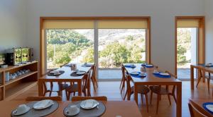 uma sala de jantar com mesas e cadeiras e uma grande janela em Alojamento Santa Clara em Manteigas