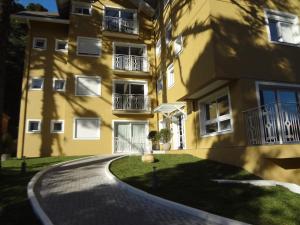 un edificio de apartamentos amarillo con una entrada sinuosa en Apartamento 105 da Borges en Gramado