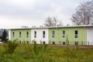 ein grünes und weißes Gebäude mit Vögeln auf dem Dach in der Unterkunft Topmotel in Oberegging