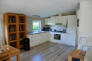 a kitchen with white cabinets and a wooden floor at Villa Pantano in Berkhout