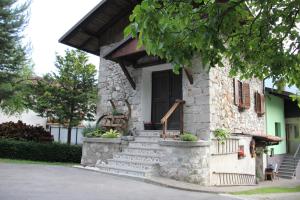 a stone house with stairs and a black door at Apartma Skednj in Kobarid