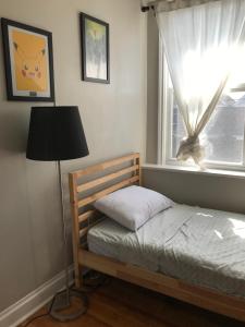 ein Schlafzimmer mit einem Bett, einer Lampe und einem Fenster in der Unterkunft Doucet Guesthouse in Hamilton