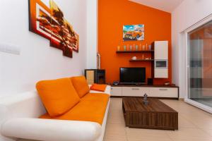 an orange living room with a couch and a tv at Seafront Apartment Soline With Seaview in Soline