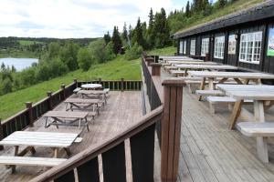 a row of tables and benches on a wooden deck at Gamlestølen Fjellstue in Etnedal