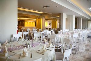 a banquet hall with white tables and white chairs at Margarita Hotel - All Inclusive in Laganas