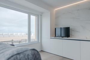 a bedroom with a large window and a tv at Studio Koksijde in Koksijde