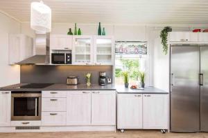 a kitchen with white cabinets and a stainless steel refrigerator at Villa Sjöman - with seaview in Alskat
