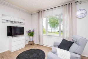 a living room with a couch and a tv and a window at Villa Sjöman - with seaview in Alskat
