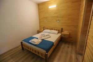 1 dormitorio con 1 cama con pared de madera en Tunays Pansiyon, en Cıralı