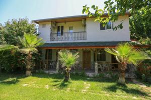 a house with palm trees in front of it at Tunays Pansiyon in Cıralı