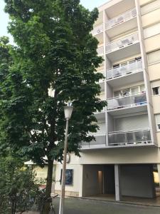 an apartment building with a tree and a street light at Studio 5 Near Basel Airport in Saint-Louis