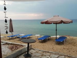 stół, krzesła i parasol na plaży w obiekcie Marti Resort w mieście Skála Sotíros