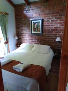 a bed in a room with a brick wall at Cabañas Spa Bungalows Huarranchi in Pucón