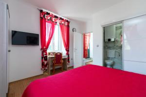a bedroom with a red bed and red curtains at Marica Guesthouse in Vela Luka
