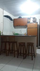 a kitchen with a counter with stools and a sink at casa de temporada coroados in Guaratuba